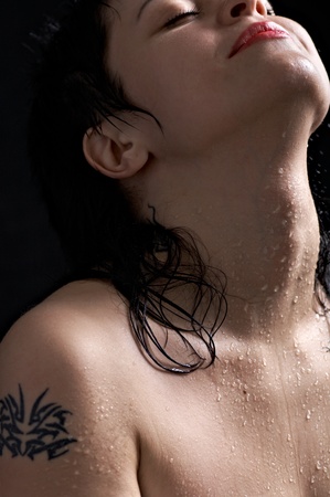 portrait of the sexual brunette in drop of water on black backgroundの写真素材