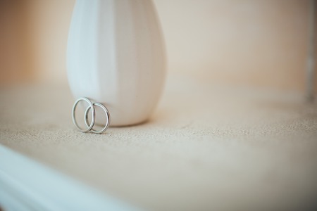Beautifull wedding rings on the white table with designer vaseの写真素材
