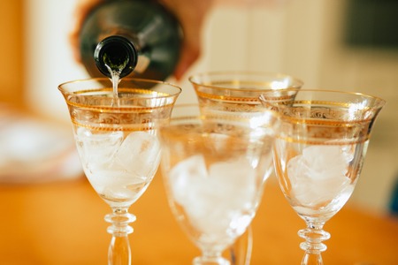 Pouring champagne into a glasses standing on table with waiter handの写真素材