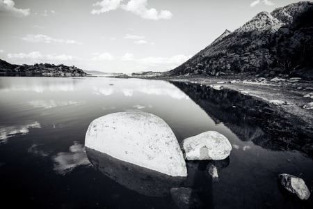 Blue lake idill under cloudline sky with rocks and stonesの写真素材