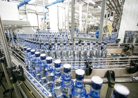 Many bottles on conveyor belt in factory, production of russian traditional alcohol drink vodka