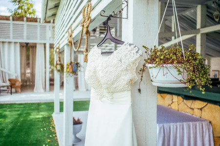 Closseup beadwork decorated wedding dress outside with smooth bright background of flowers and white wooden tent  and lace curtainsの写真素材