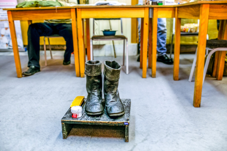 Vintage shoes at shoe shine point on the wooden stand with special creme and brush with yellow tables and people backgroundの写真素材