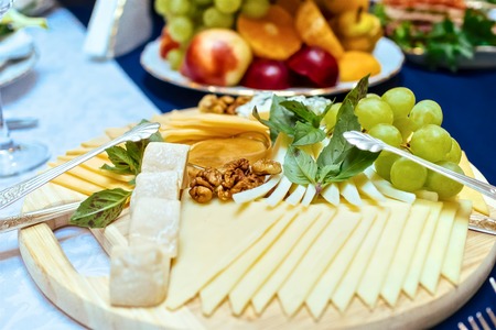 Cheese plate with cheeses Dorblu, Parmesan, Brie, Camembert with grapes and honey in serving on the tableの写真素材