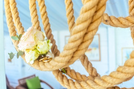 Golden wedding rings on sea rope at sunny summer dayの写真素材