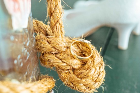 Golden wedding rings on sea rope at sunny summer dayの写真素材