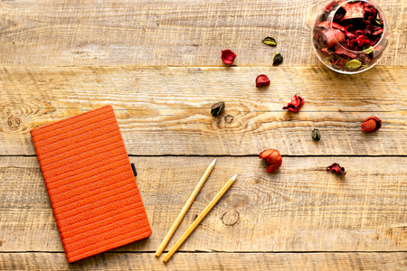 Blank notebook with pencil and flower on wooden table - womans working placeの写真素材