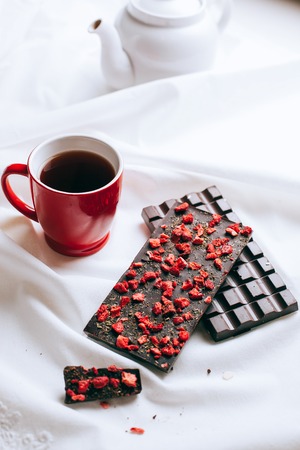 Composition of milk chocolate, white teapot and red mug