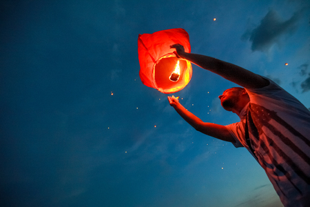 Omsk, Russia - June 16, 2012: festival of Chinese paper lantern, the man starts lantern in the sky at nightのeditorial素材