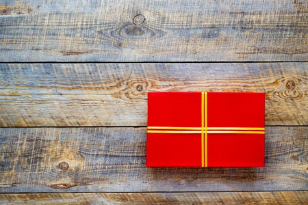 Red gift box with golden ribbon on vintage wooden backgroundの写真素材