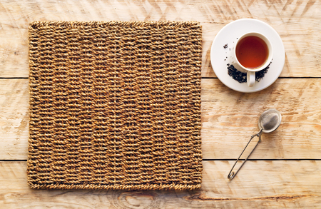 cup of tea on a wicker mat standing on wodden table - mockupの写真素材