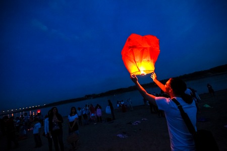 Omsk, Russia - June 16, 2012: festival of Chinese paper lantern, the man starts lantern in the sky at nightのeditorial素材