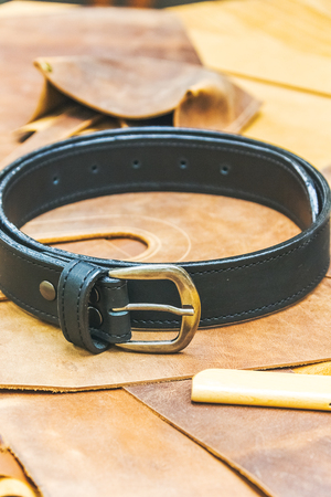 leather workshop and tools  with black belt on wodden table close upの写真素材