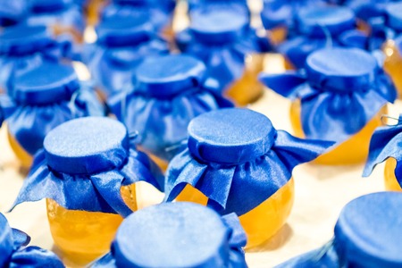 jars with yellow jam covered with blue cloth
