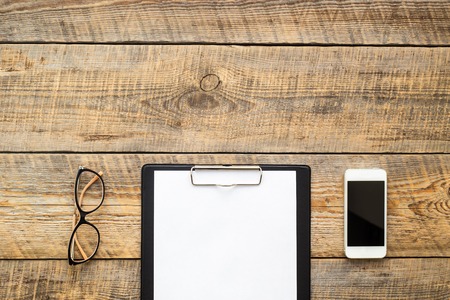 workplace at the wooden table with glasses and  white blank paperの写真素材