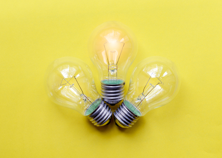 three glass bulbs for lamps - idea concept on yellow backgroundの写真素材