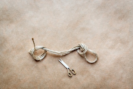 concept scissors cut the knot on rope on a background of paperの写真素材