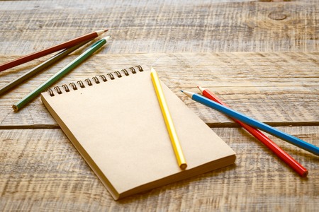 hobby painting - workplace with colored pencils, blank open notebook on wooden table