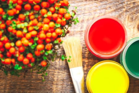 cans gouache with brush, flower with berries  on a wooden background close upの写真素材