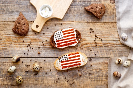 Two sandwiches with image of american flag and quail eggs on wooden table. Top view.の写真素材
