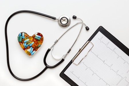 stethoscope on a white background with pills in the shape of heart and cardiogram isolated top viewの写真素材