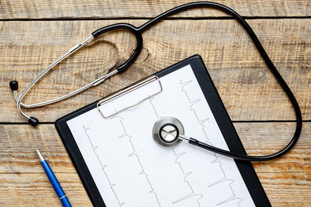 new stethoscope on wooden table with cardiogram close upの写真素材