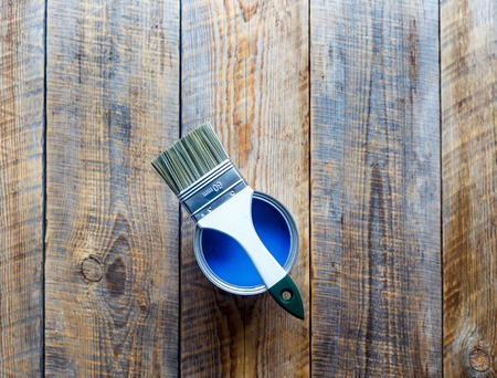 jar with blue paint and brush on the wooden background top view close up