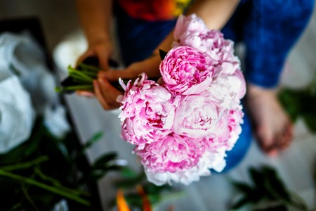 Florist making a bouguet of pink peonies in workshopの写真素材