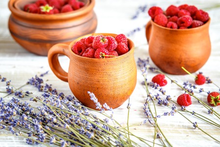 pottery with strawberries and lavender on wooden table close up