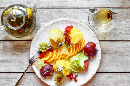 fruit salad and tea on a wooden table top viewの写真素材