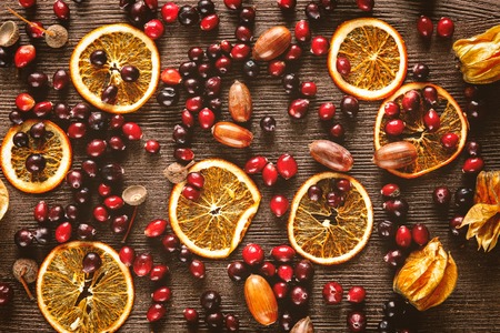Autumn still life with orange caramel and cranberries on wooden background.