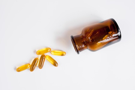 fish oil pills in glass bottle on white background close up top viewの写真素材