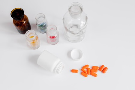 colored pills in glass bottles on white background close up view from aboveの写真素材