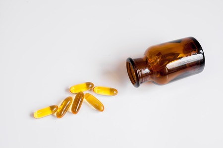 fish oil pills in glass bottle on white background close up top viewの写真素材