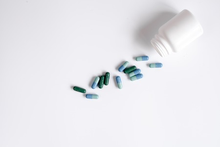 tablets in plastic container on white background top view