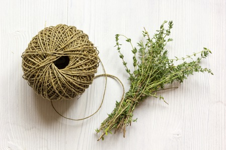 bundle of thyme and twine on wooden background top view.の写真素材