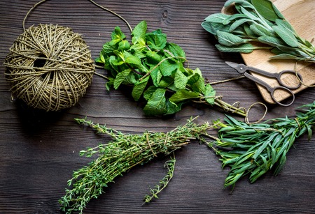 bundle of sage and thyme, mint, estragon on wooden board top view.の写真素材
