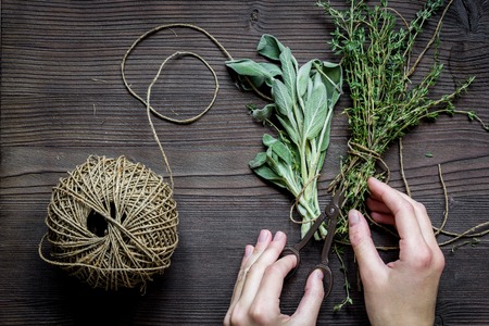 thyme and sage on wooden background with hands top view.の写真素材