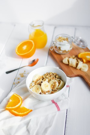 healthy breakfast bowl of yogurt with granola and banana on wooden backgroundの写真素材