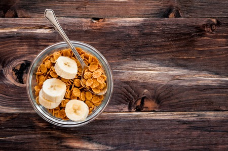 flakes in bowl with banana on dark wooden background top viewの写真素材