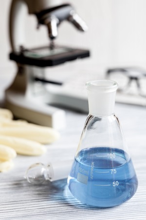 beaker with blue liquid on background microscopeの写真素材