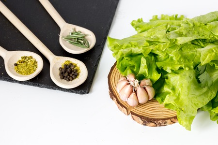 spices for cooking in spoon and fresh salad on white background close upの写真素材