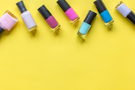 lot of bottles of nail polish on yellow background top viewの写真素材