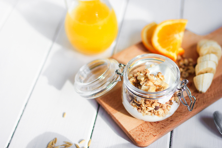 healthy breakfast bowl of yogurt with granola and banana on wooden backgroundの写真素材