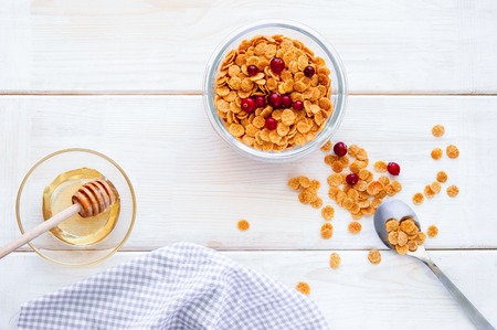 flakes in bowl with berries, coffee on wooden background top view