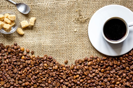 coffee beans with coffe cup, cane sugar on linen cloth background top view.の写真素材
