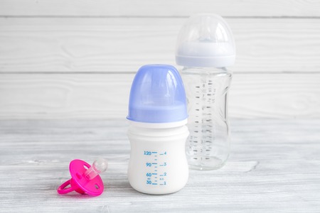 baby bottle with milk on wooden background close up
