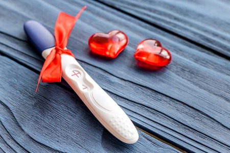 Positive pregnancy test with heart on dark wooden background top viewの写真素材