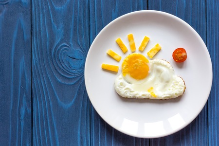 sunshine fried eggs breakfast for kid on blue background and napkin top viewの写真素材