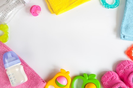 baby bottle with milk and towel, baby rattle, booties on white background top view